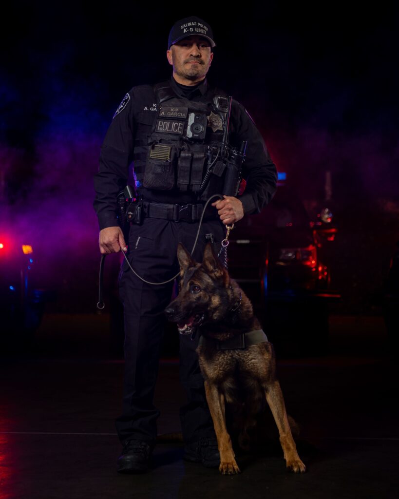 Salinas police officer and his dog posing in front of a white background