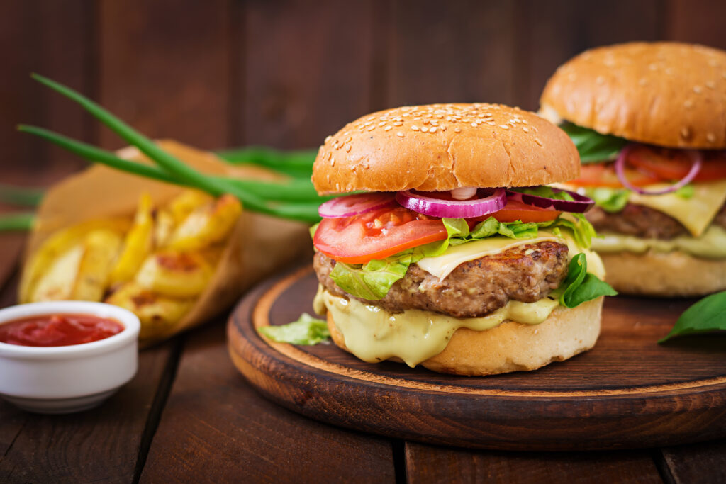  Gourmet burger with melted cheese, crispy lettuce, and juicy tomato slices.