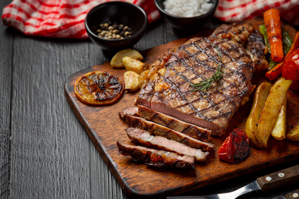 Sizzling steak cooked to perfection, adorned with grill marks and served with a side of vegetables.